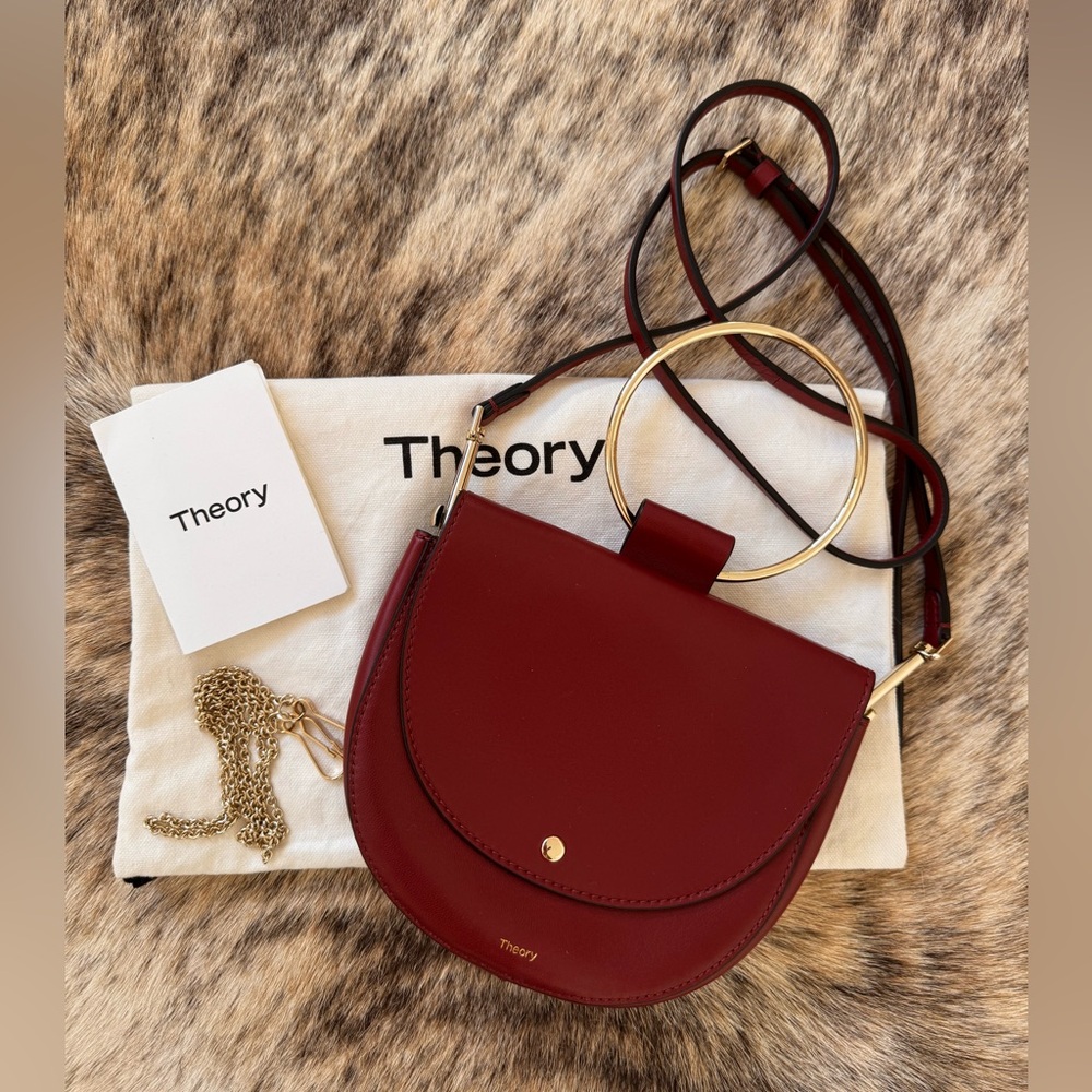 THEORY. Signature brick red, leather hoop bag, with a gold handle.